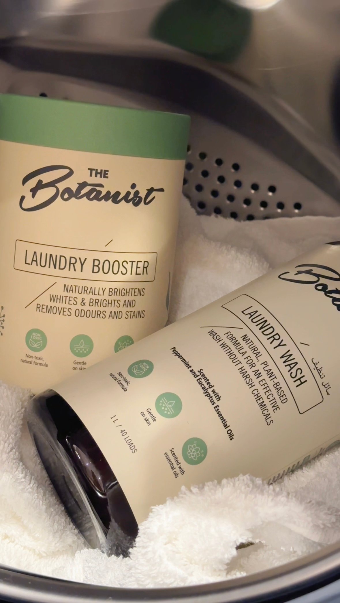 Two laundry products, a laundry booster and a laundry wash, displayed on a white towel in a laundry basket.