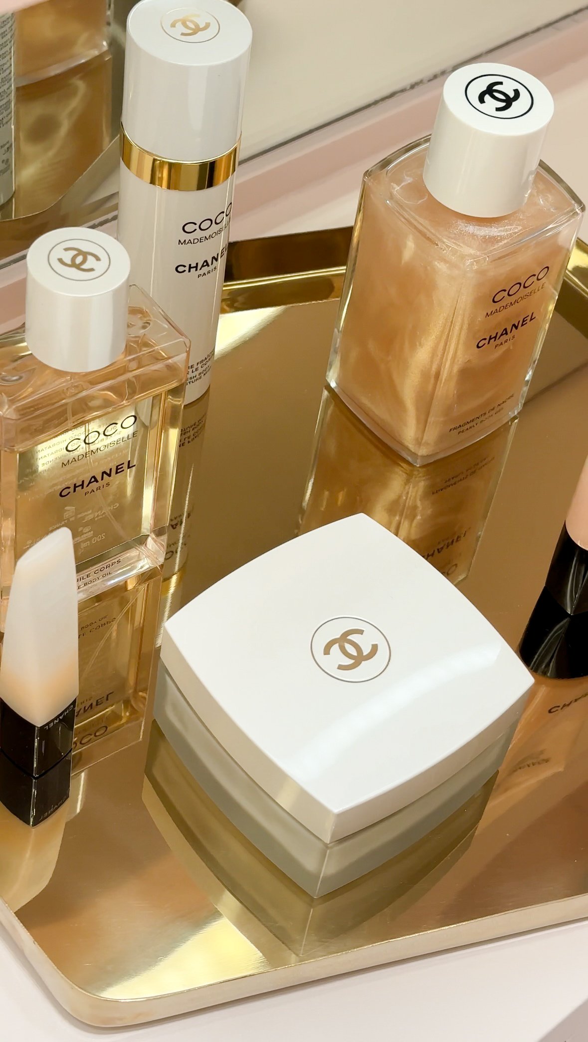 Chanel beauty products arranged on a reflective tray, showcasing a variety of skincare and fragrance items.