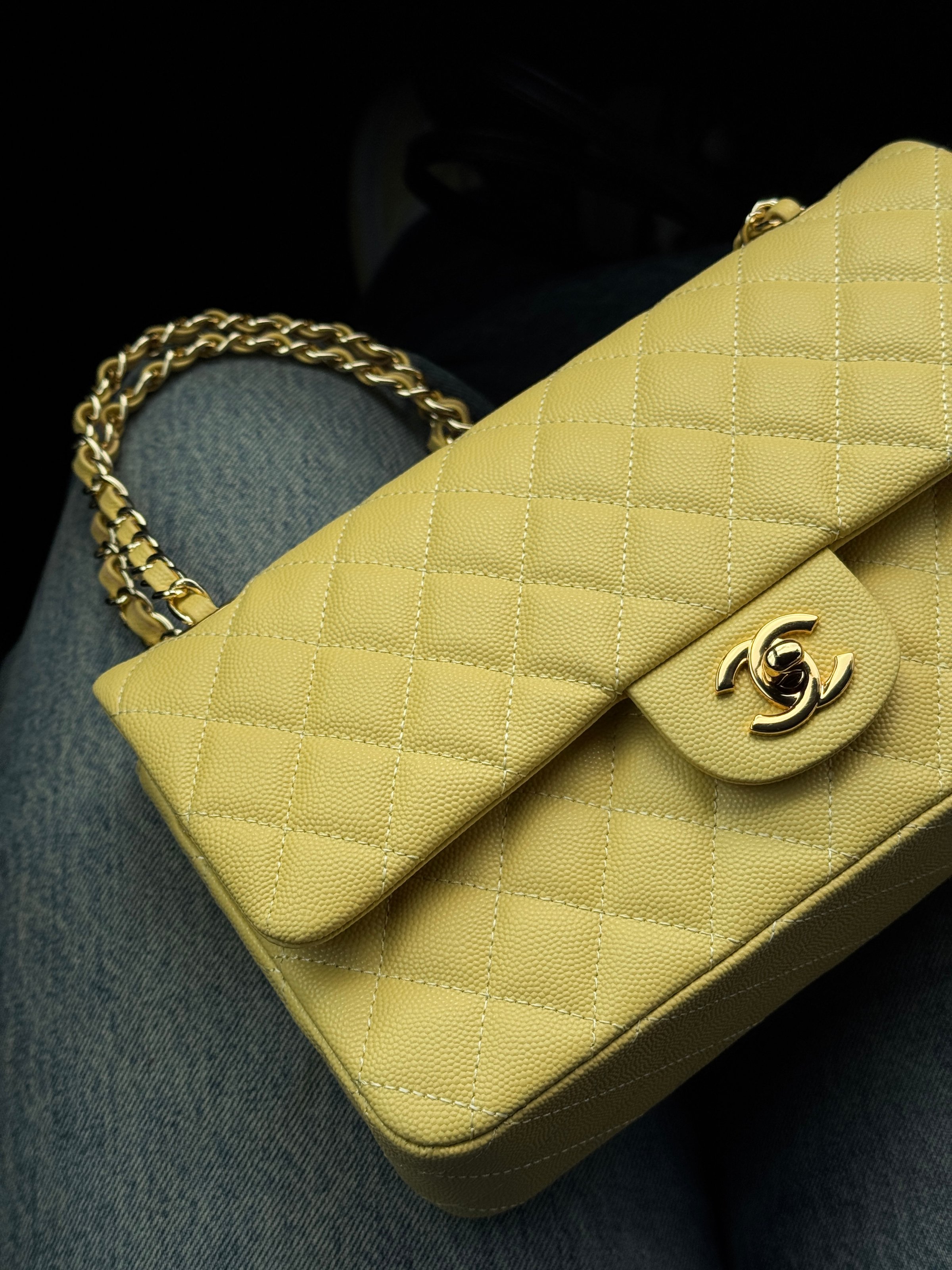 A yellow quilted handbag with a gold chain strap, featuring the iconic Chanel logo.