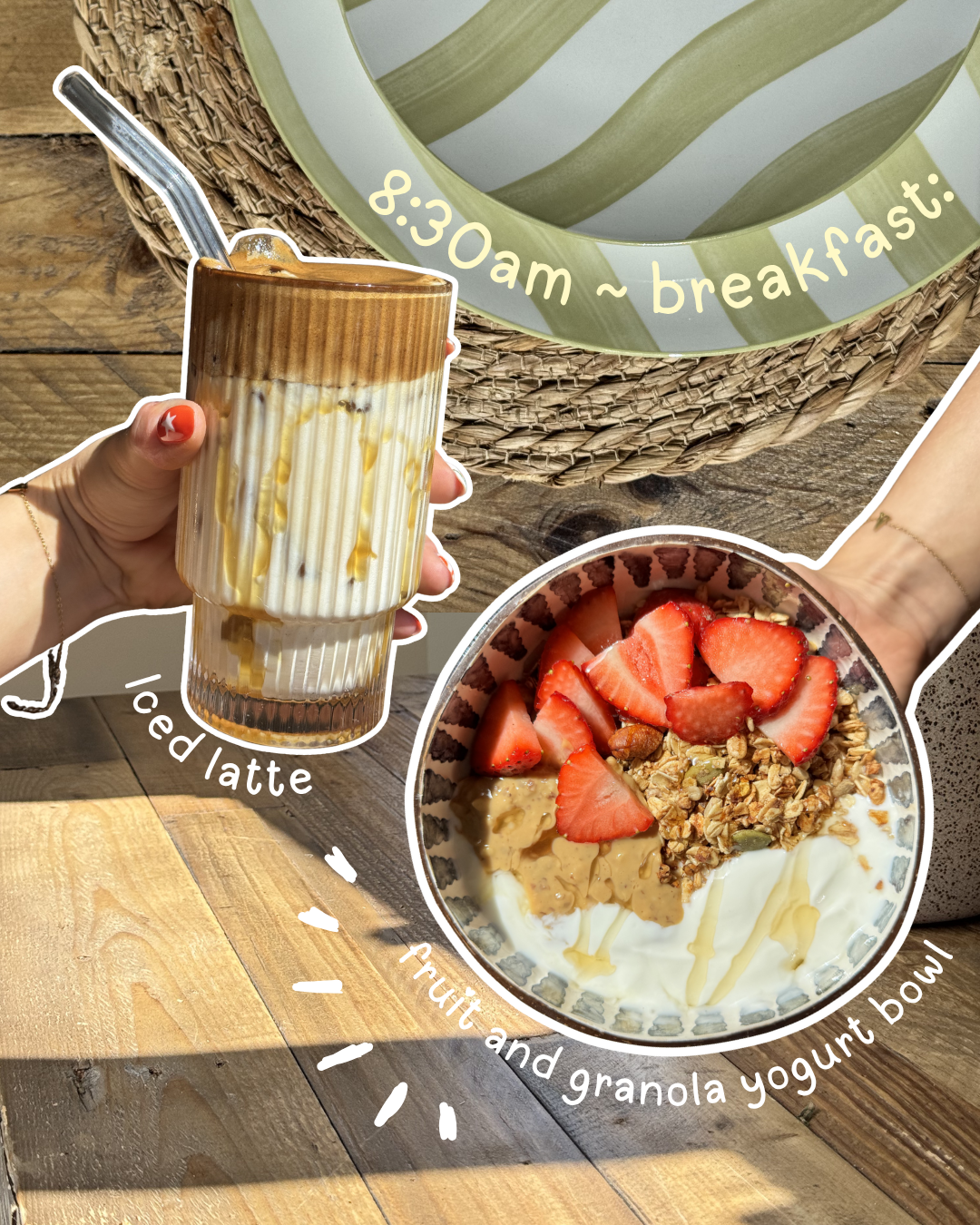 A hand holding a glass of iced latte next to a bowl of fruit and granola yogurt topped with strawberries, set against a rustic wooden background.