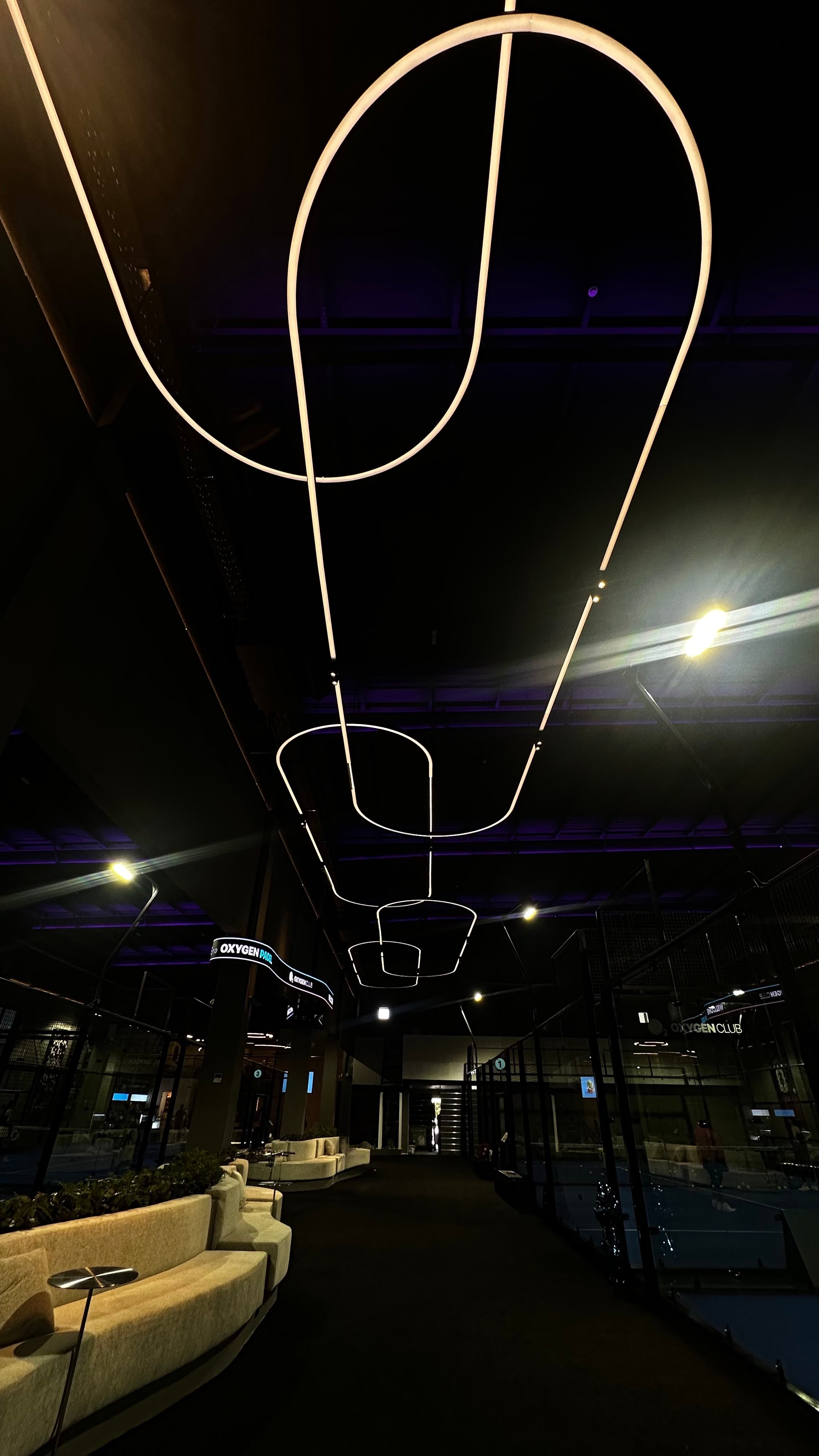 A modern interior space featuring unique overhead lighting designs and a sleek, minimalist aesthetic.