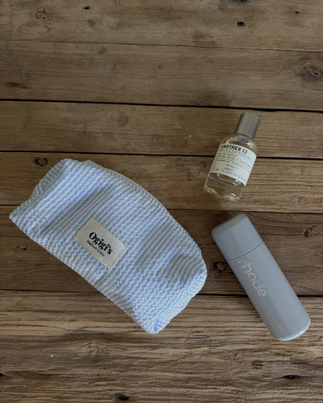 A flat lay arrangement featuring a striped headband, a small bottle of skincare serum, and a sleek gray water bottle on a wooden surface.