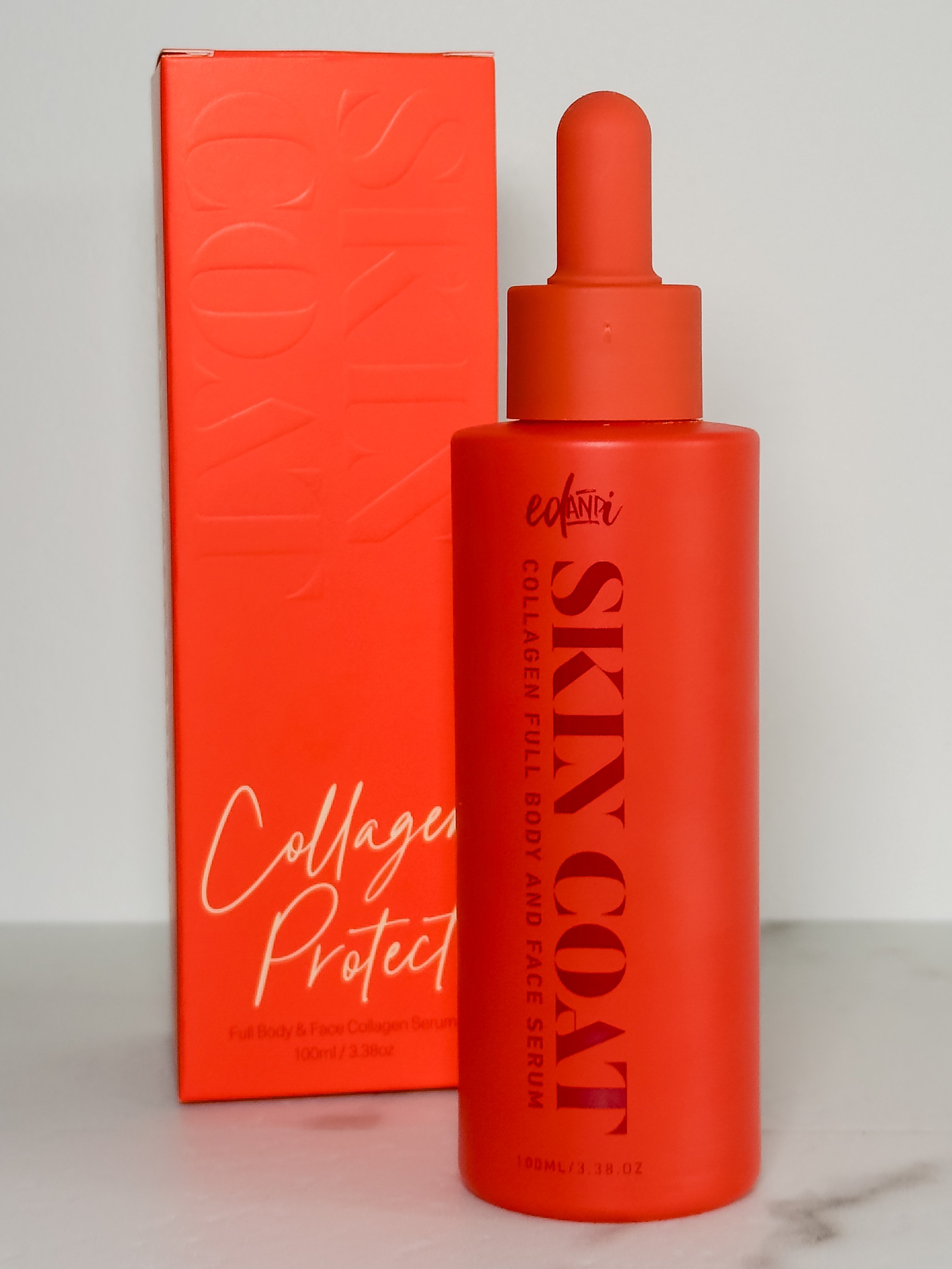 A vibrant red serum bottle labeled 'Skin Coat' next to its matching box, both featuring bold typography.