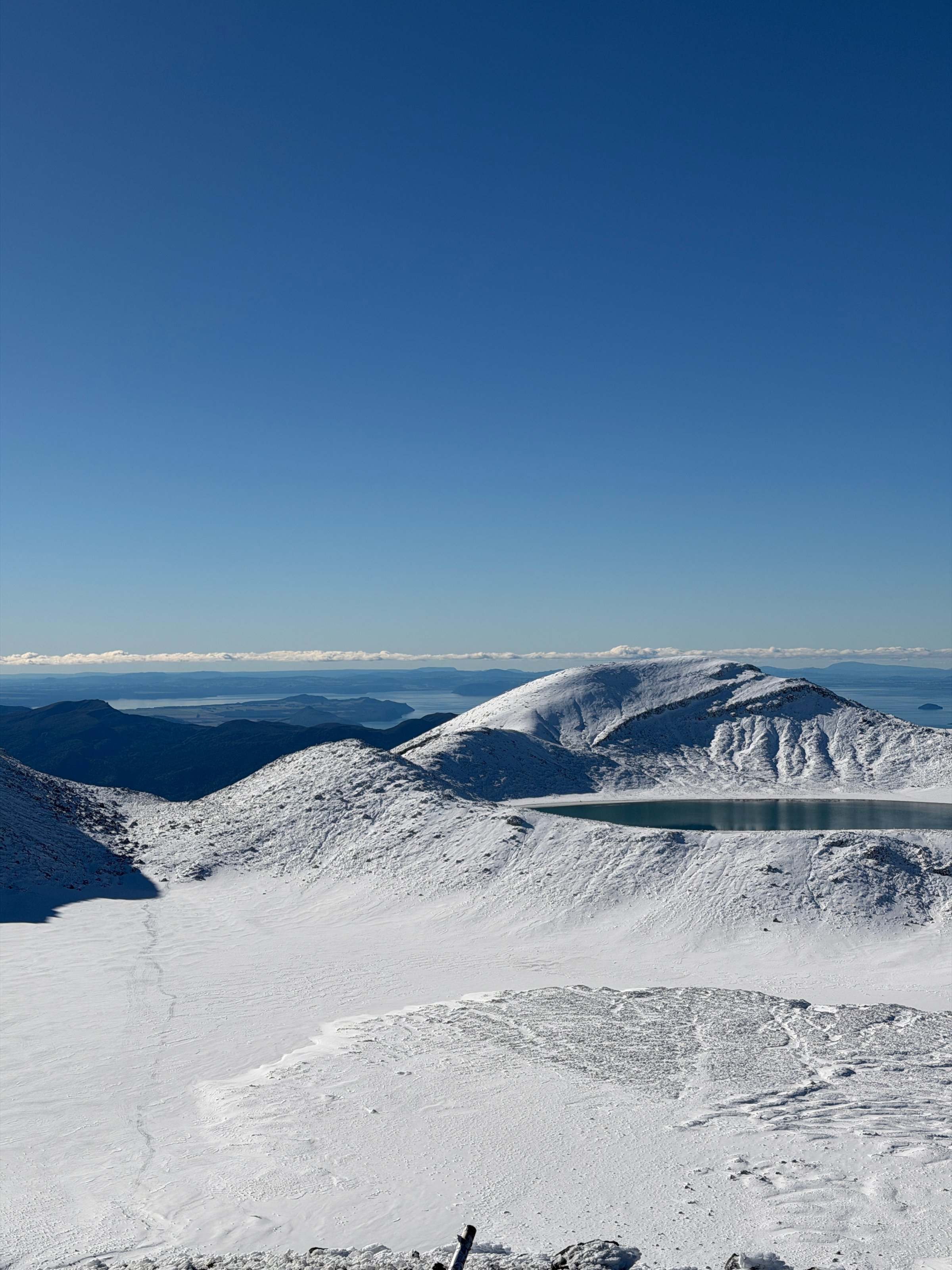 A panoramic view of snow-covered mountains under a clear blue sky, showcasing a serene landscape.