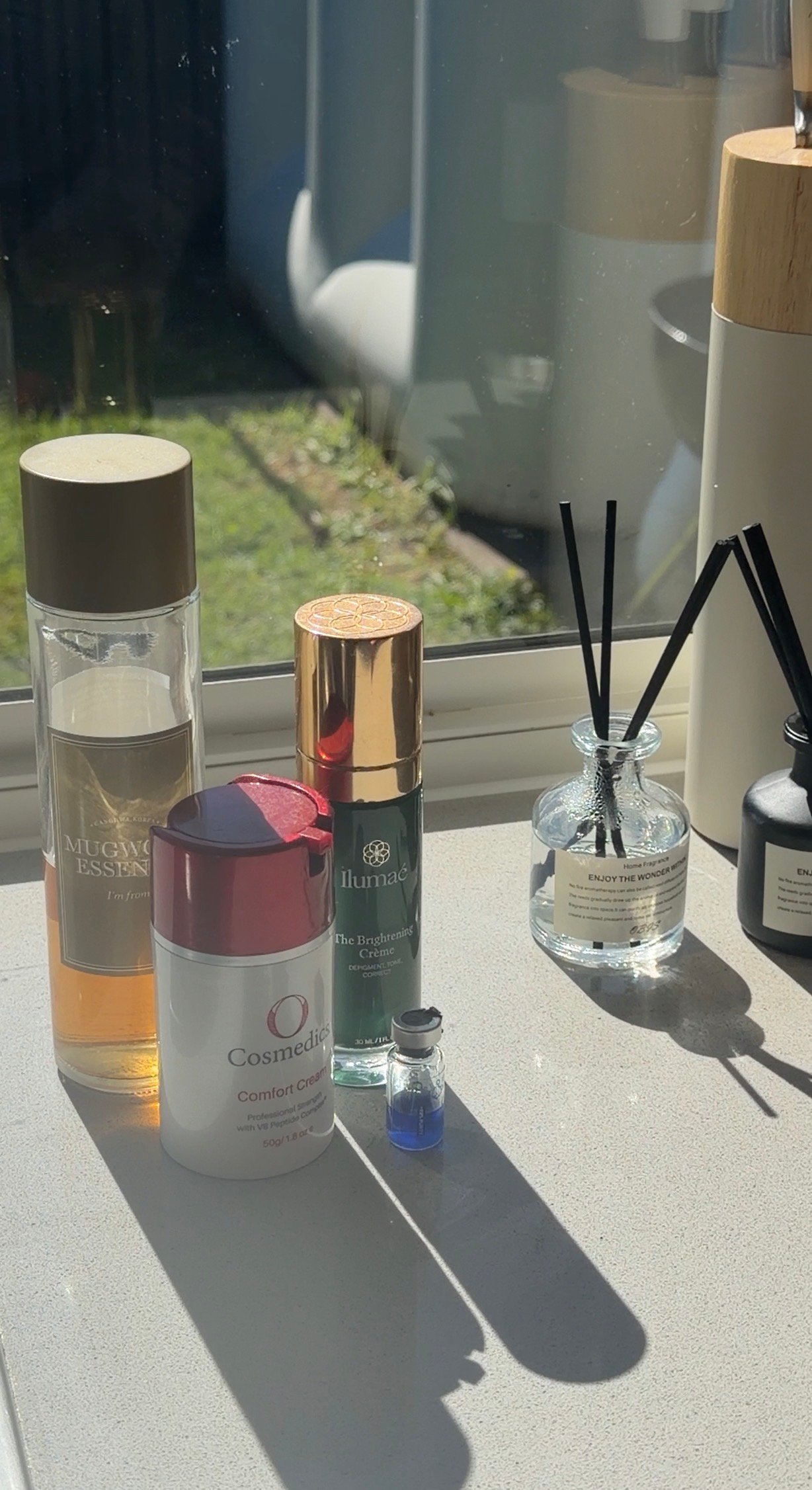 A collection of skincare products displayed on a countertop, including serums and creams, with natural light illuminating the scene.