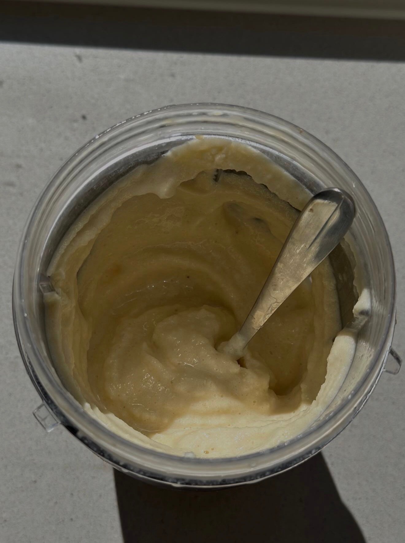 A close-up view of a jar containing a creamy substance, with a spoon resting inside.