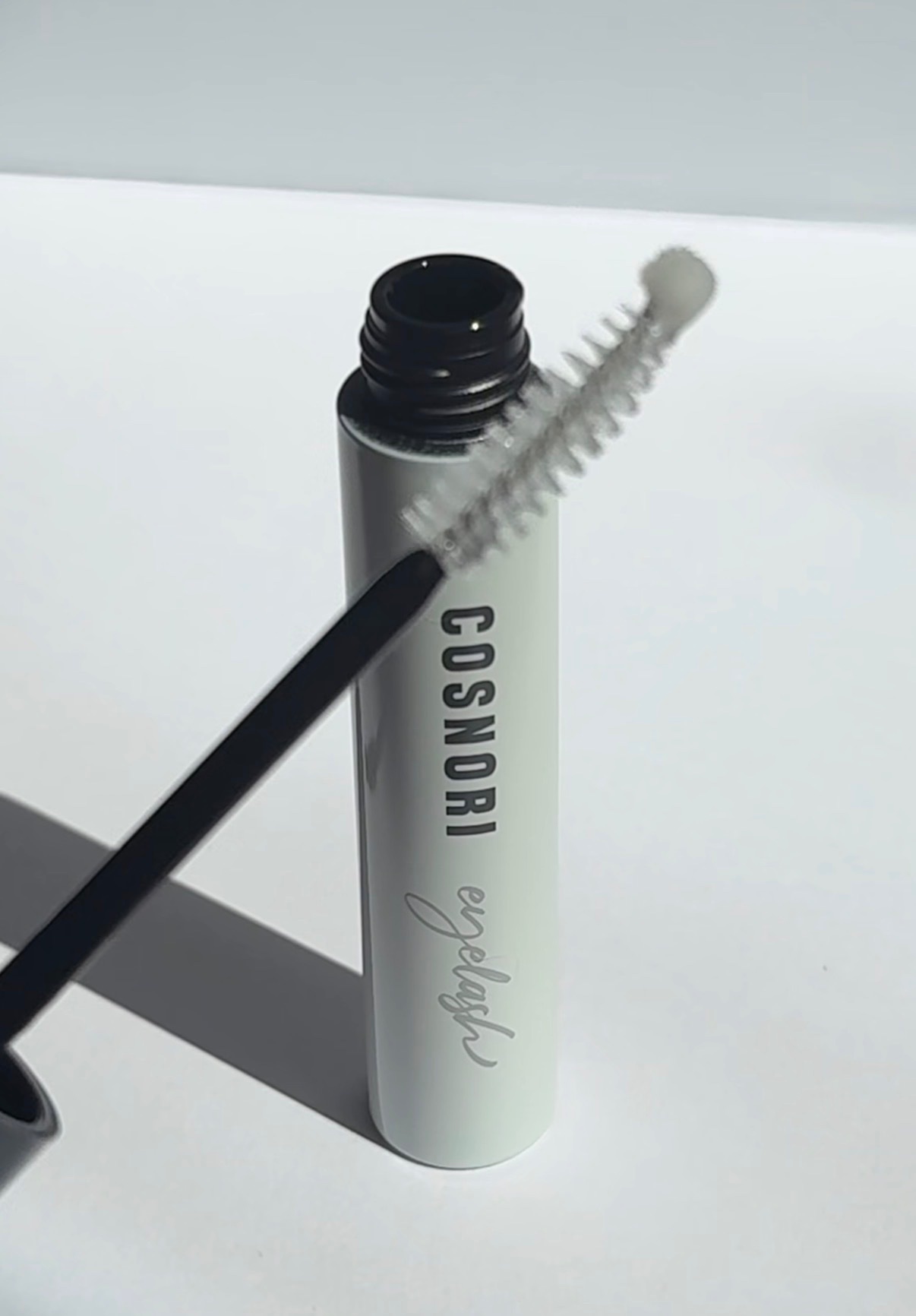 A close-up of a mascara tube with a brush, showcasing the product's design and branding.