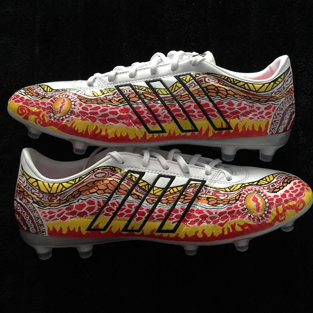A pair of custom-designed soccer cleats featuring vibrant red, orange, and yellow patterns with intricate details.