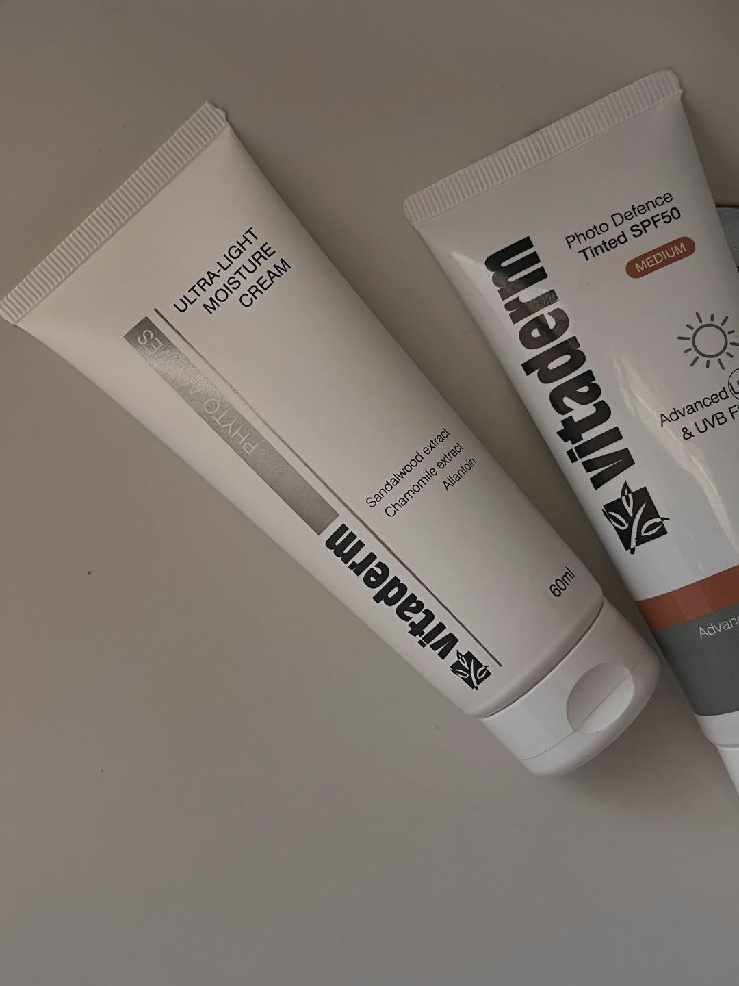 Two skincare products displayed side by side, featuring a moisturizer and a tinted sunscreen with SPF50.