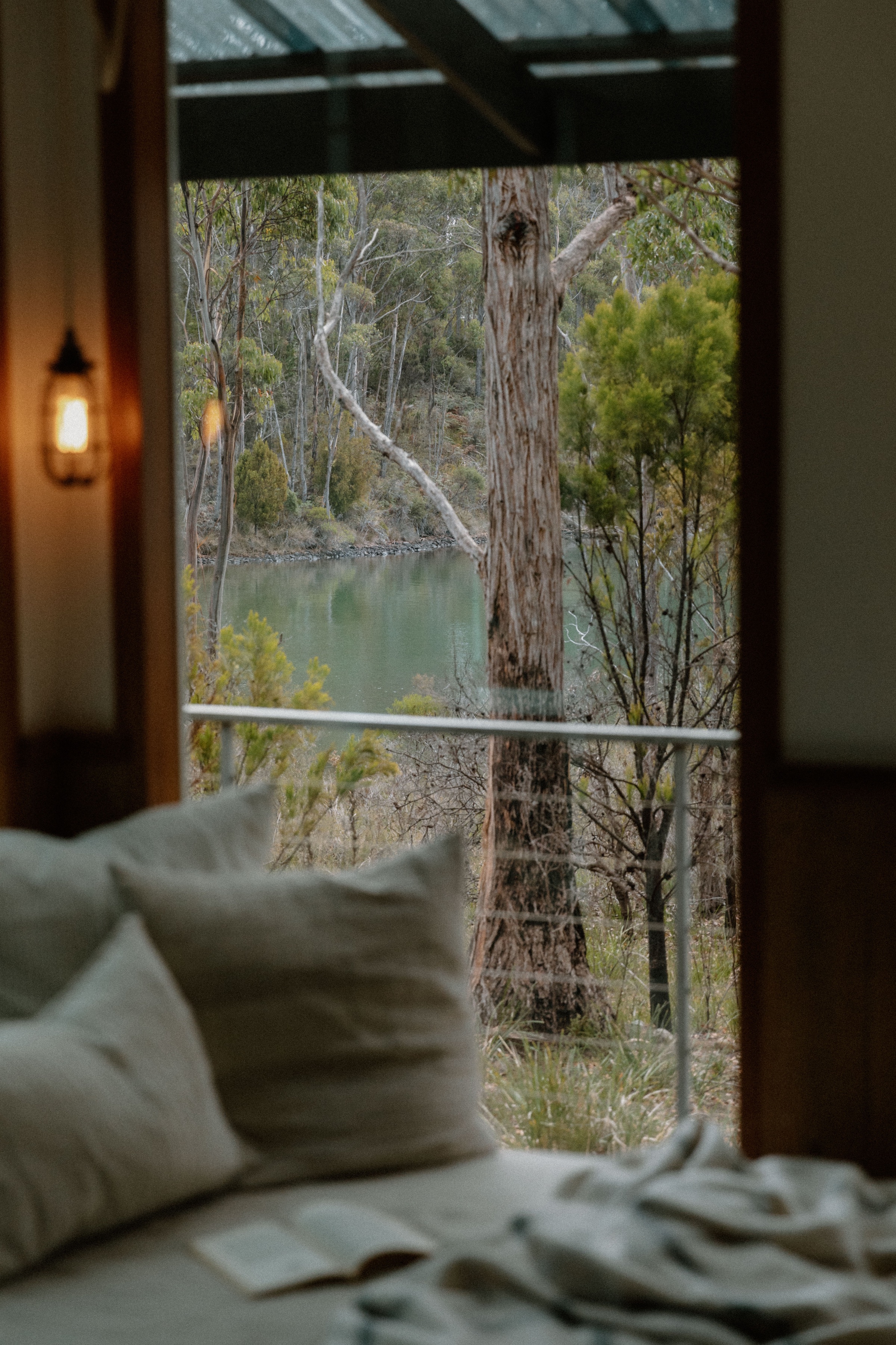 A serene view from a cozy interior, showcasing a tranquil outdoor scene with trees and water visible through a window.