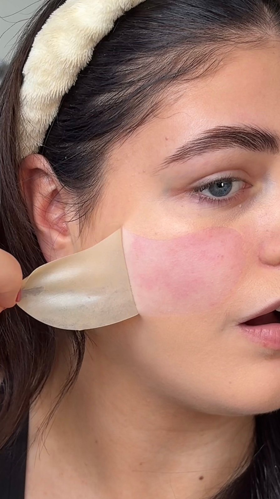 A close-up of a person applying a skincare product to their face, showcasing the texture and application process.