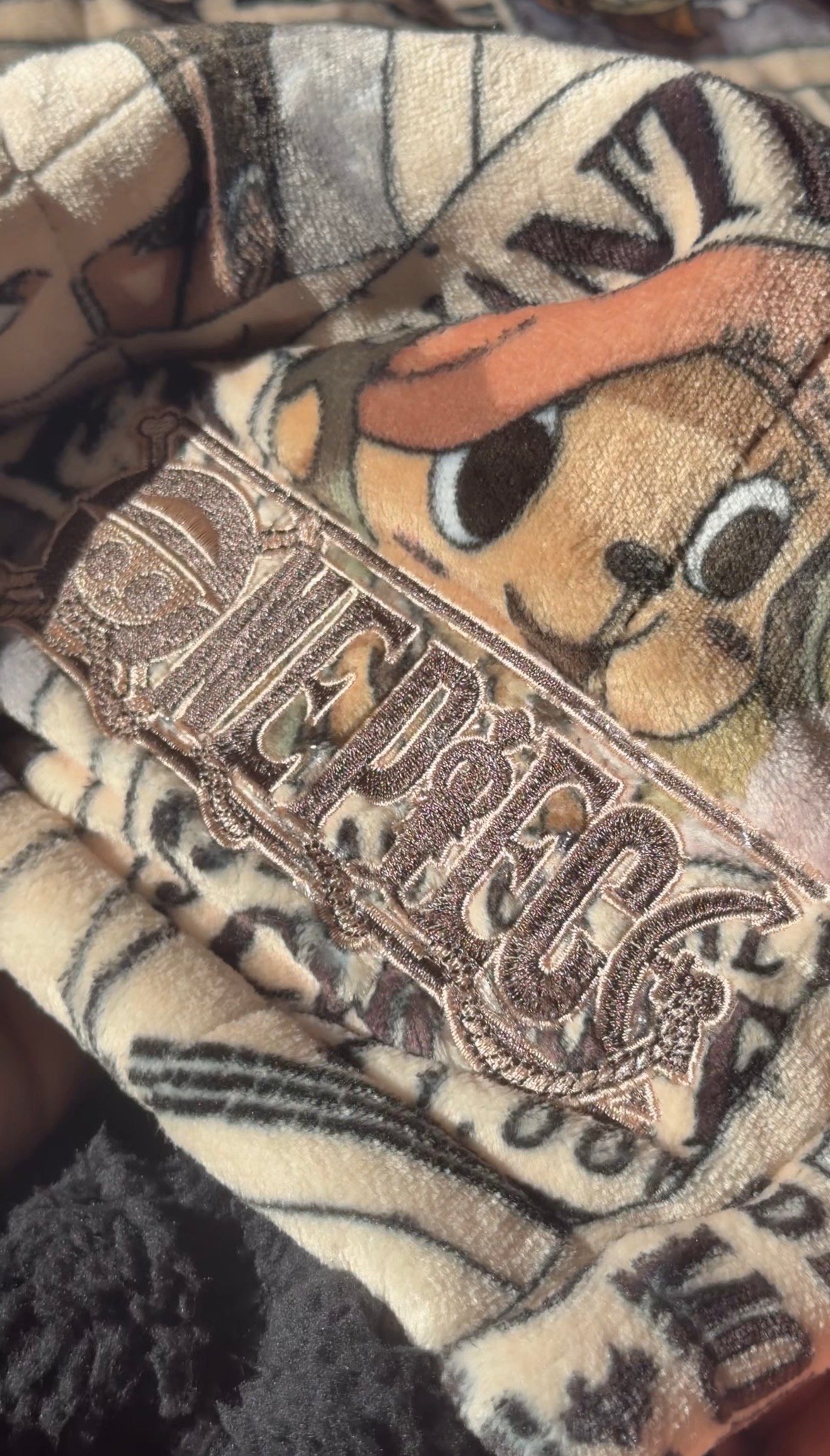 Close-up of a patterned fabric featuring a cartoon character with a logo tag visible.