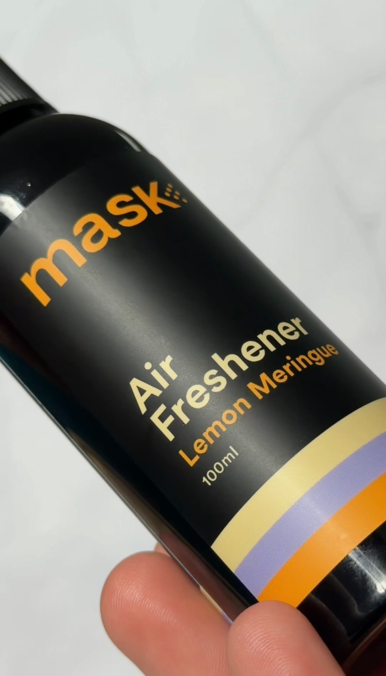 A close-up of a black air freshener bottle labeled 'mask Air Freshener Lemon Meringue' with a colorful design.