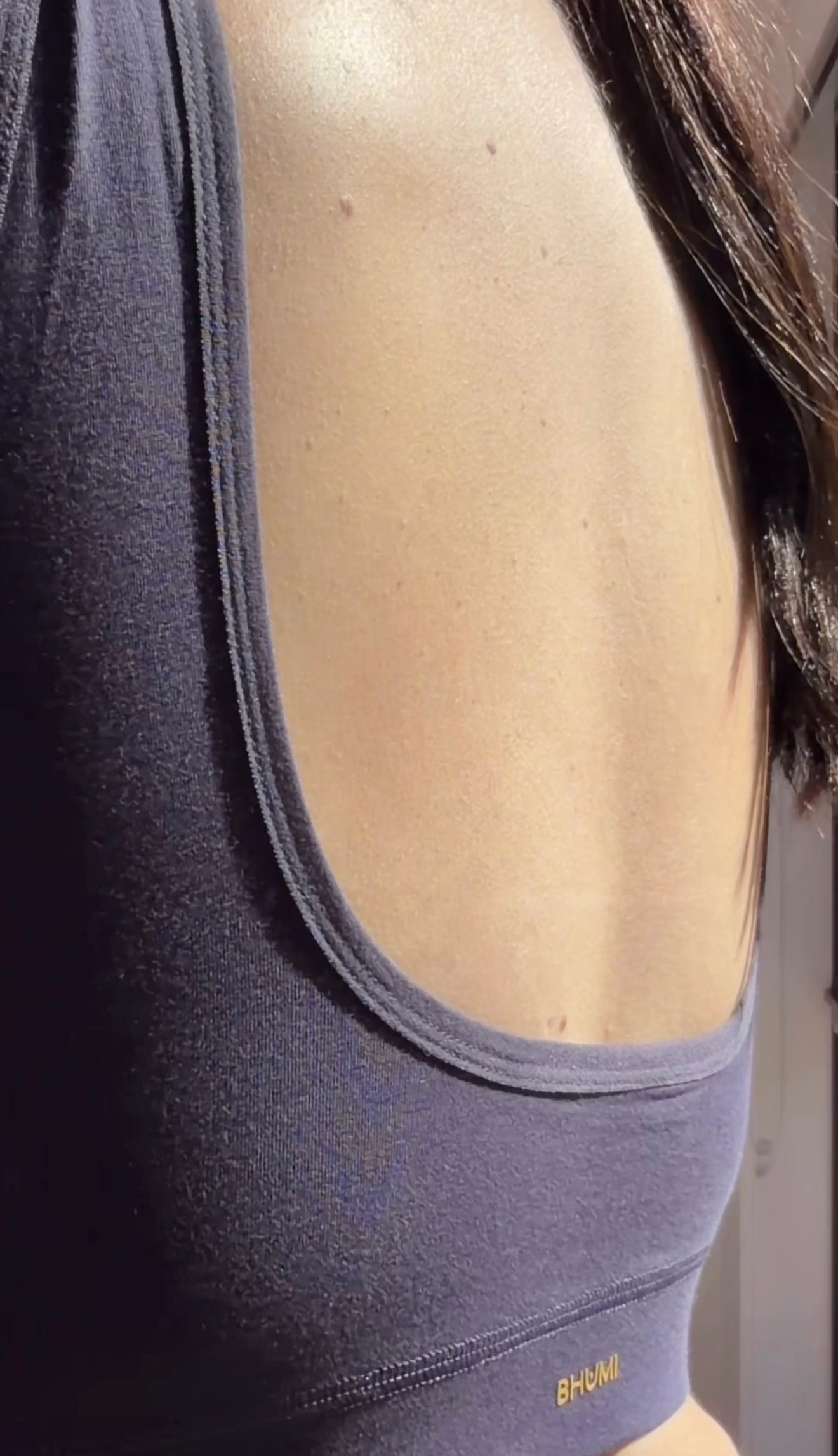 A close-up shot of a person's back, showcasing a dark-colored sports bra with a low-cut design.