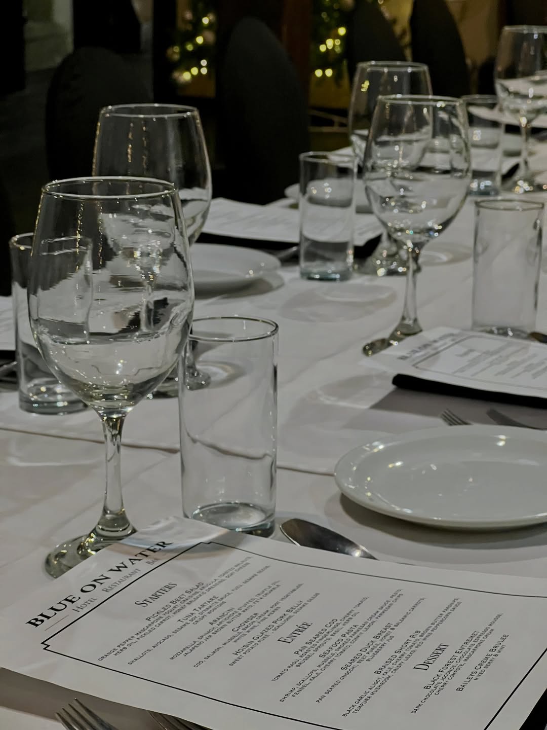 A beautifully arranged dining table set with glassware and menus, creating an elegant atmosphere for a meal.