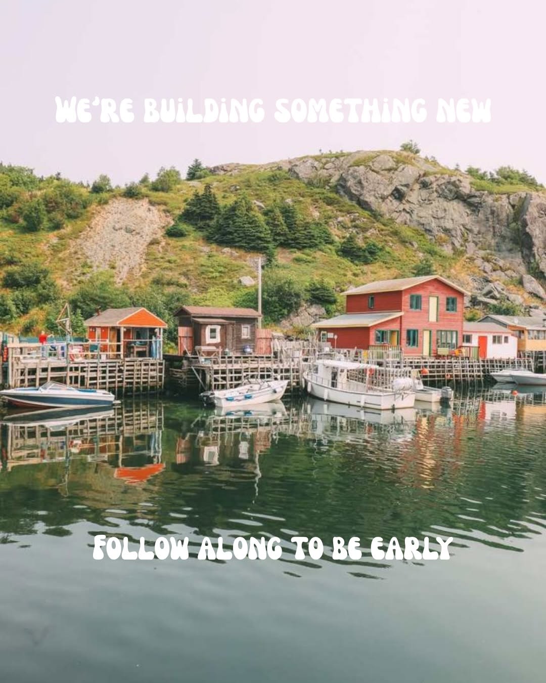 A scenic view of a harbor with colorful houses and boats reflecting on the water, surrounded by lush greenery and rocky hills.