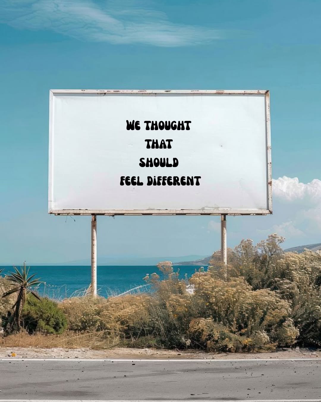 A billboard by the seaside displaying the text 'WE THOUGHT THAT SHOULD FEEL DIFFERENT' against a clear blue sky and ocean backdrop.