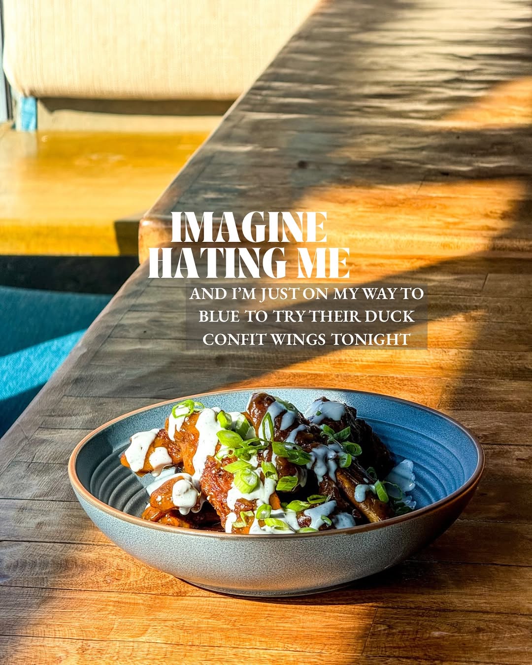 A beautifully plated dish of duck confit wings garnished with green onions, set on a wooden table with soft lighting.