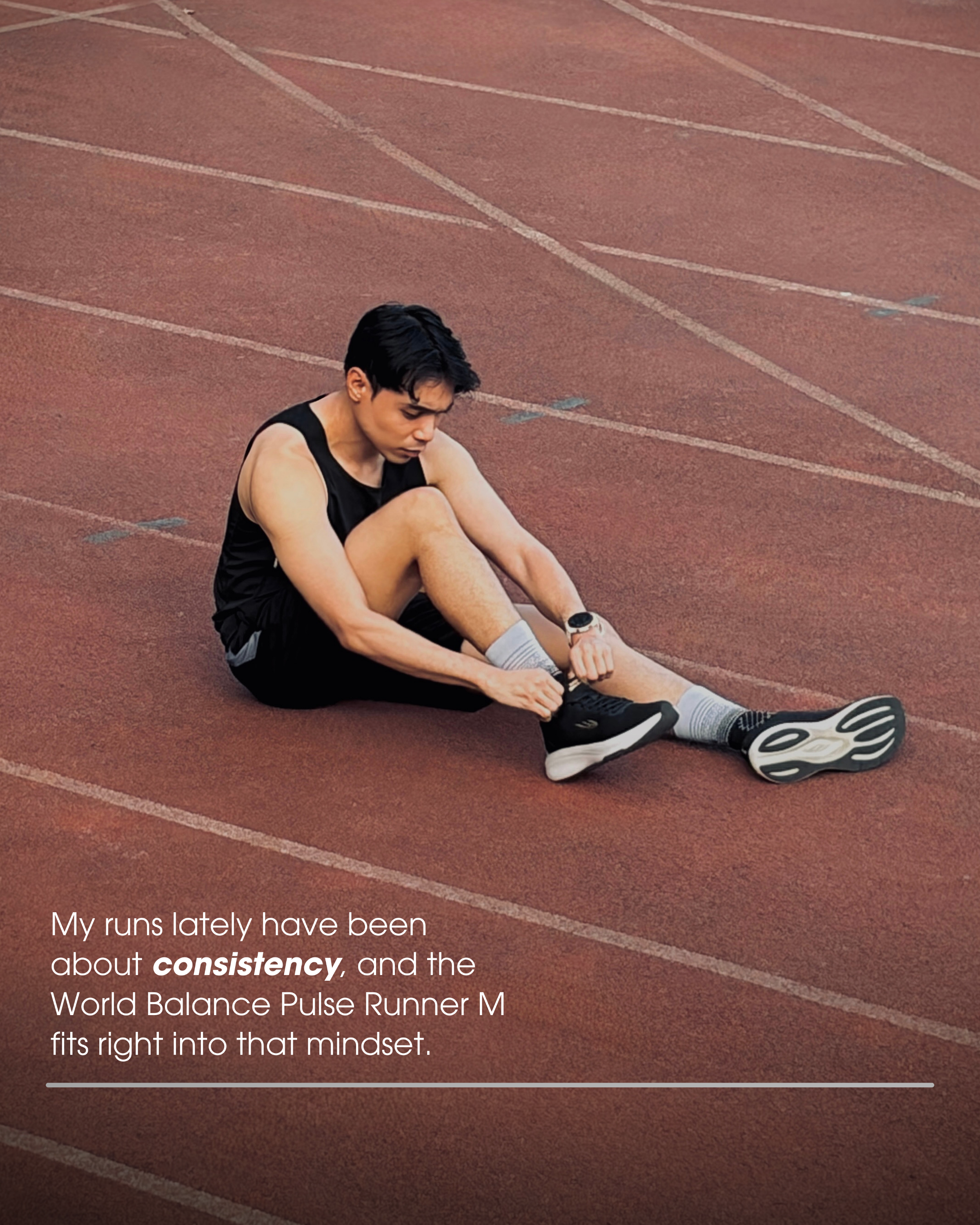 A young man sits on a running track, tying his shoe while wearing athletic gear, reflecting a focus on consistency in his running routine.