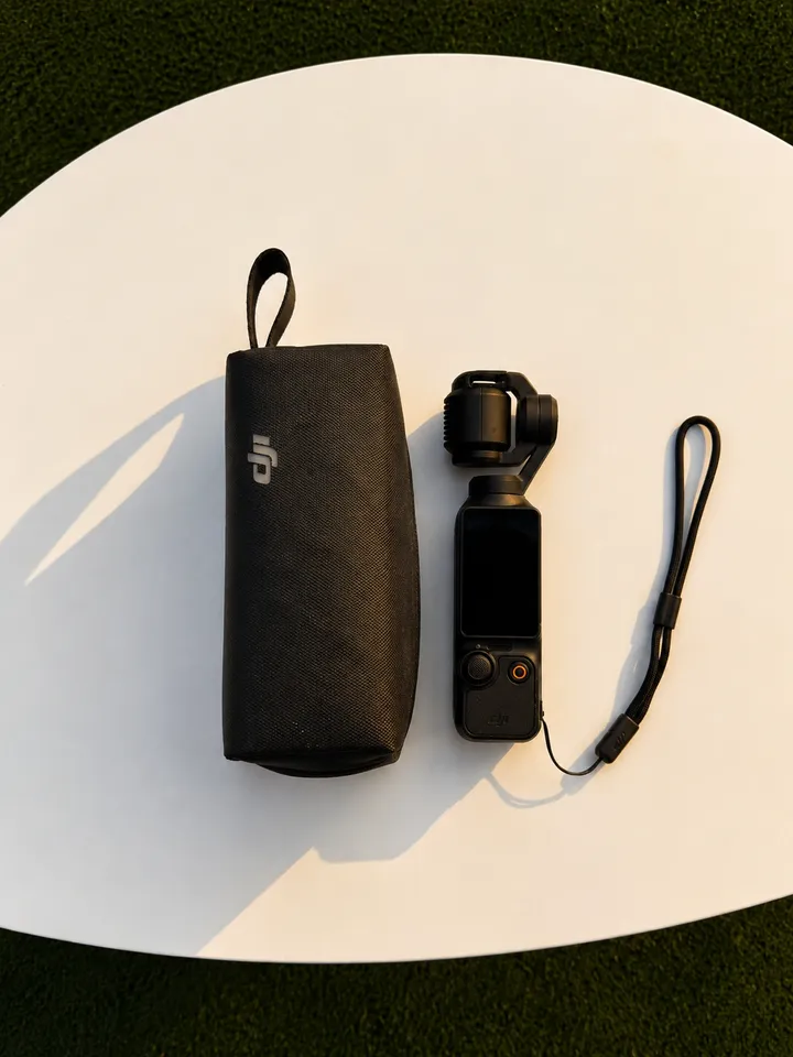 A compact camera and its protective case resting on a white surface.