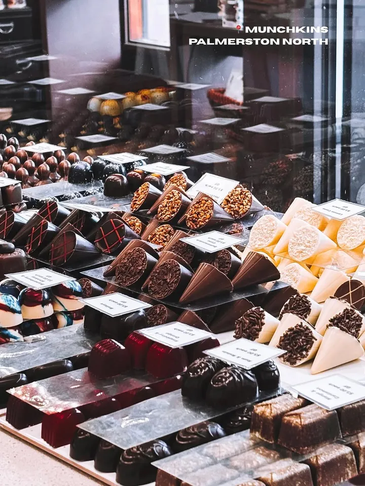 A display of assorted chocolates arranged neatly in a shop, showcasing various shapes and flavors with labels.